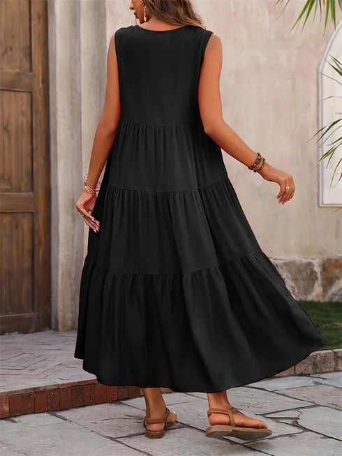 Woman wearing a black sleeveless dress with a layered skirt, standing outdoors.